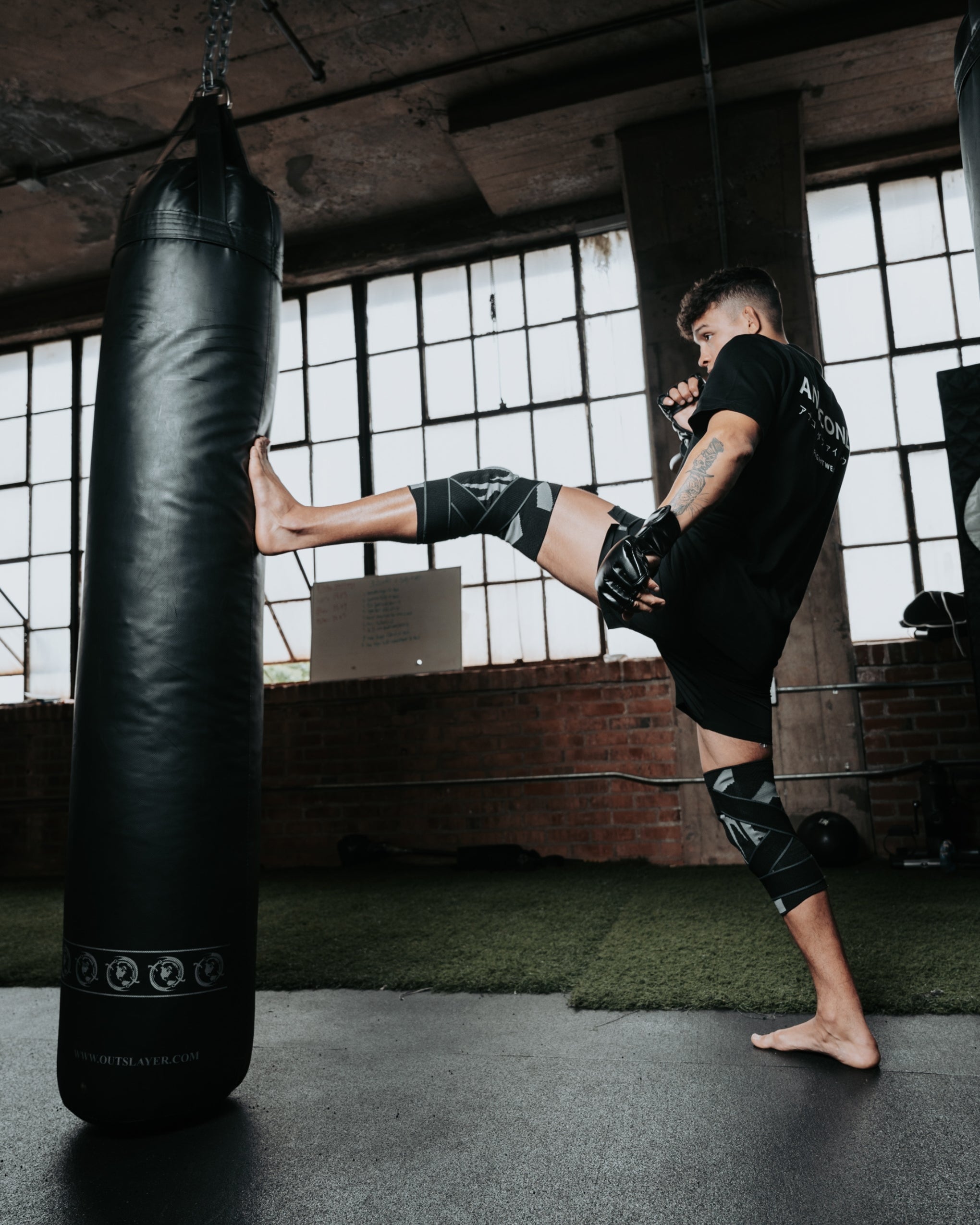 Man in rash guard and knee brace kneeling and looking at the camera.